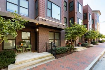 A brick building with a patio and a tree in front.
